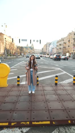 young woman waiting on a city street with coffee