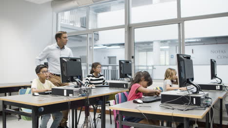 Computer science teacher watching as pupils doing task