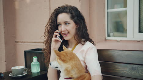 woman talking on phone with dog in a cafe