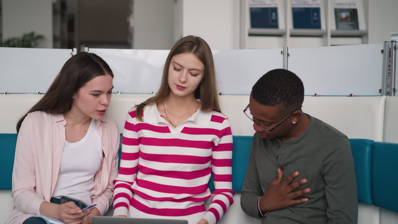 los estudiantes discuten información de internet en la biblioteca. los empleados jóvenes con portátiles trabajan en proyectos en premisas de coworking. programa de aprendizaje electrónico en la universidad