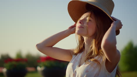 pretty girl taking off sunhat in summer day. cheerful woman enjoying sunlight.