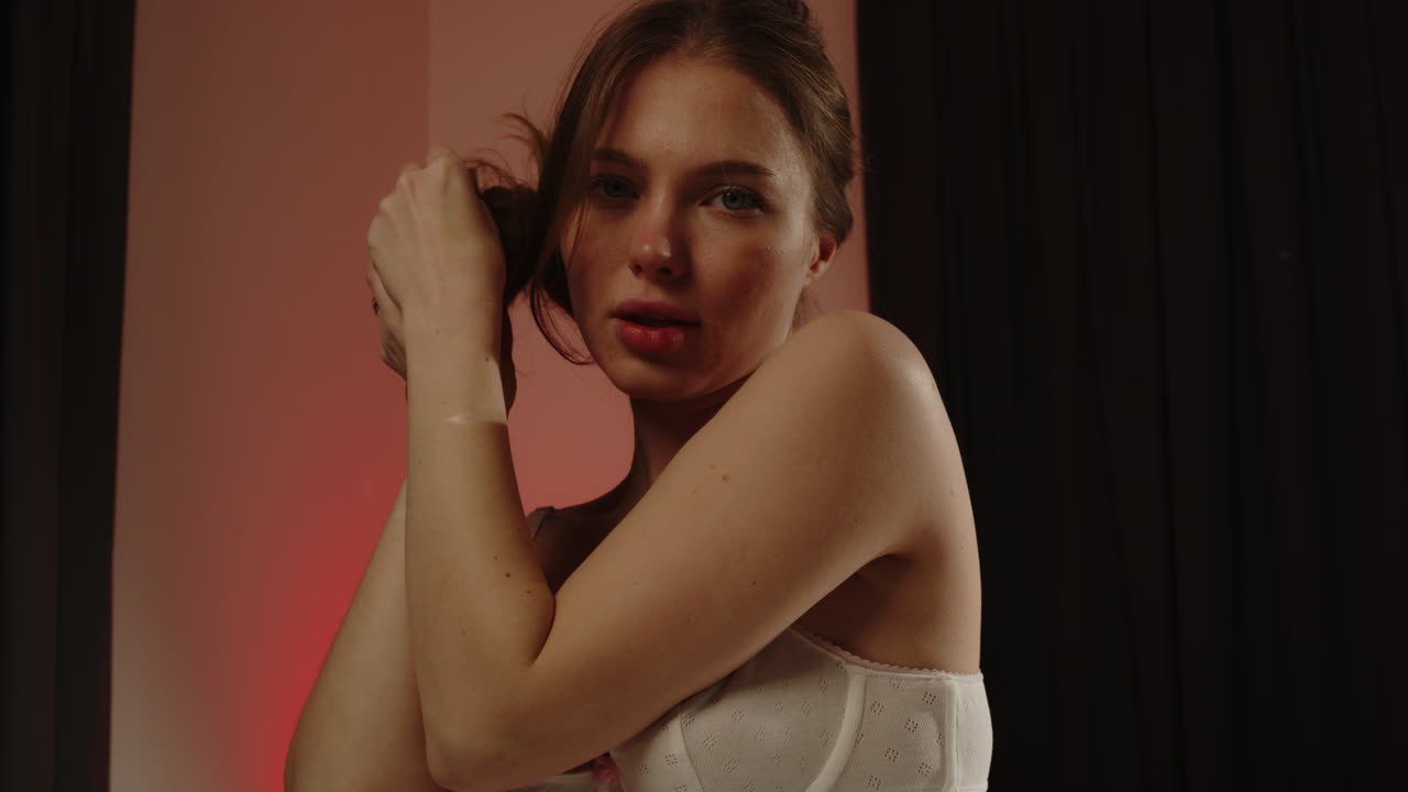 Stunning low angle dolly of a beautiful woman wearing a white brassier sensually playing with her hair in slow motion
