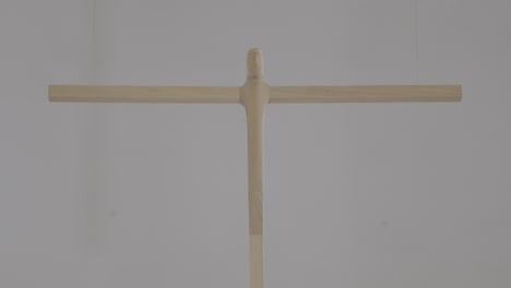 a large, carved wooden cross hangs in a church, camera pans from bottom to top