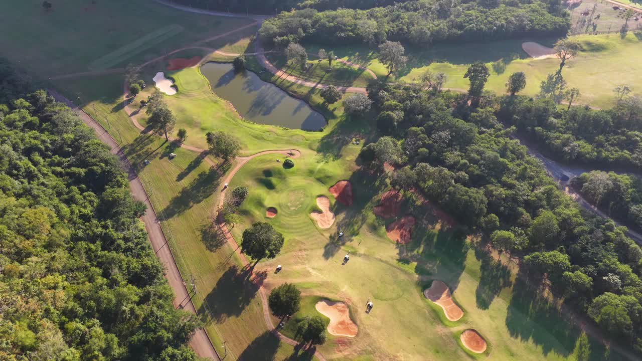 Una toma aérea cenital con dron revela un campo de golf con búnkeres de arena y obstáculos de agua