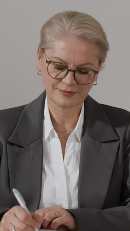 mature businesswoman writing in notebook