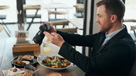 stylish young man takes pictures on a mirrorless camera dishes at the table