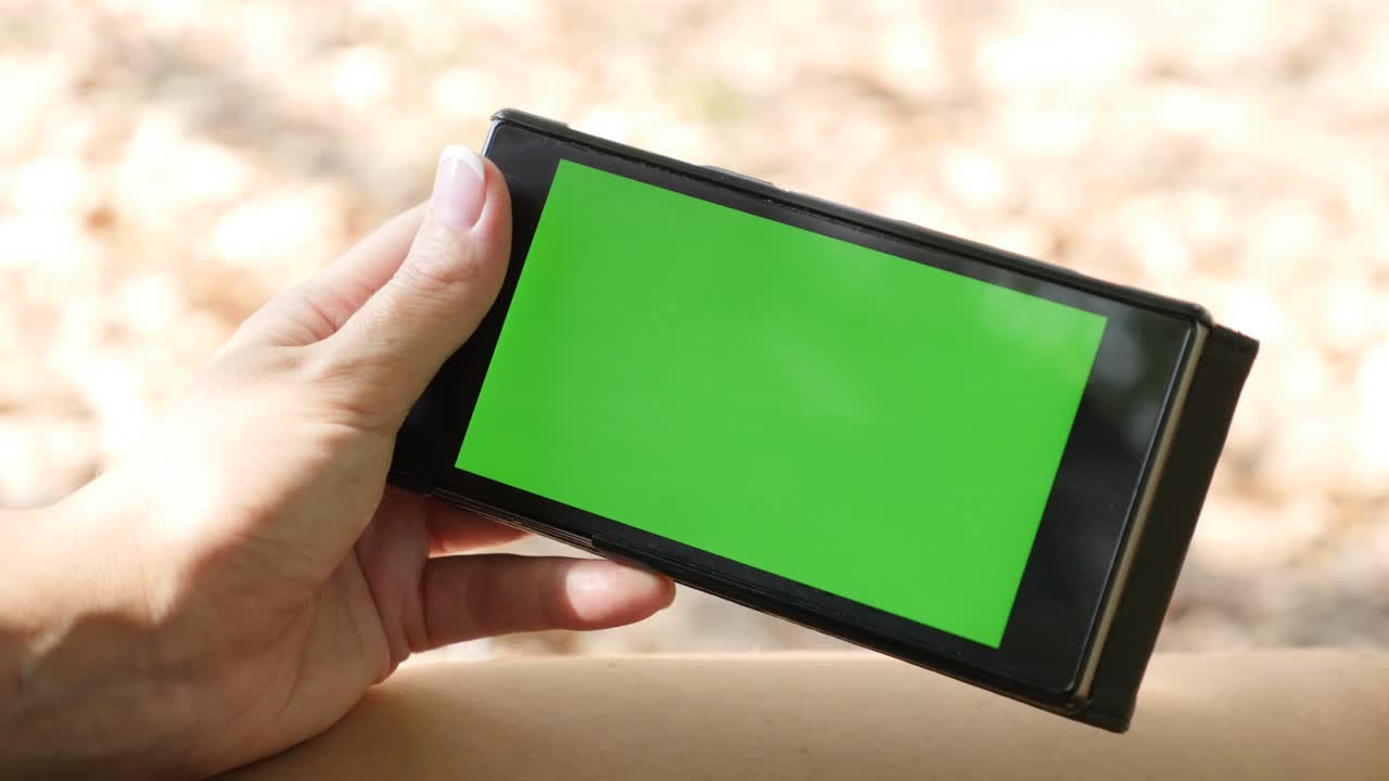 fondo al aire libre de otoño con mujer sosteniendo pantalla verde teléfono 4k