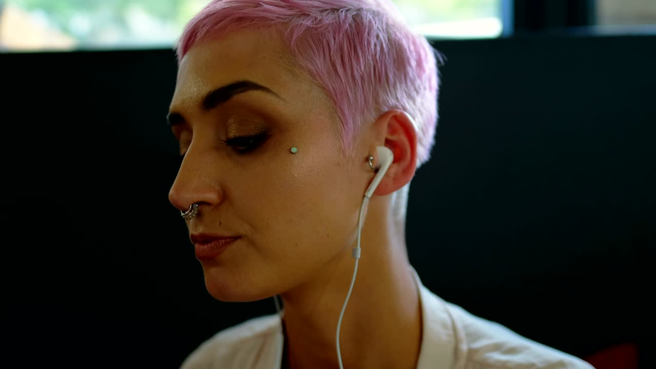 mujer escuchando música mientras usa una computadora portátil en un café 4k