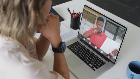 mujer de negocios caucásica usando una computadora portátil para una videollamada con un colega de negocios afroamericano