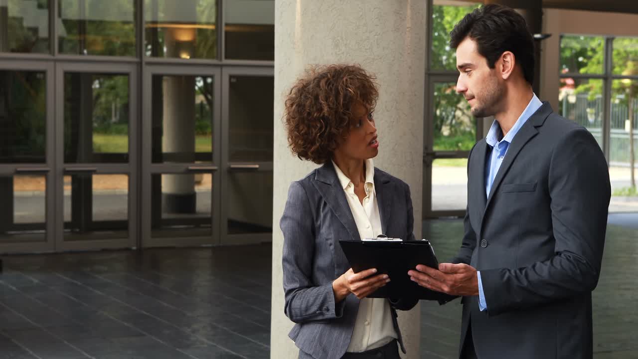 Businesspeople discussing over clipboard