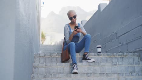 mixed race woman using smartphone on staircase