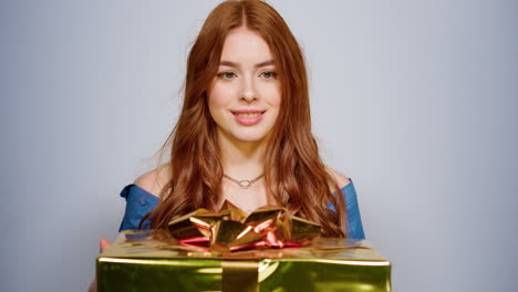 portrait of excited woman holding gift. girl shaking present box indoors