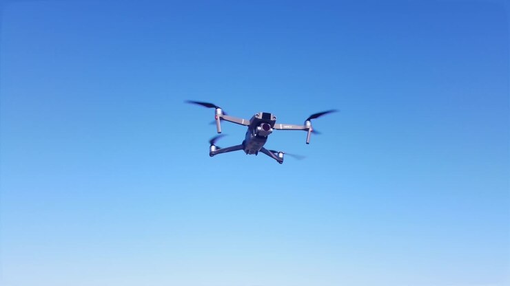 A drone hovers in front of a beautiful blue sky