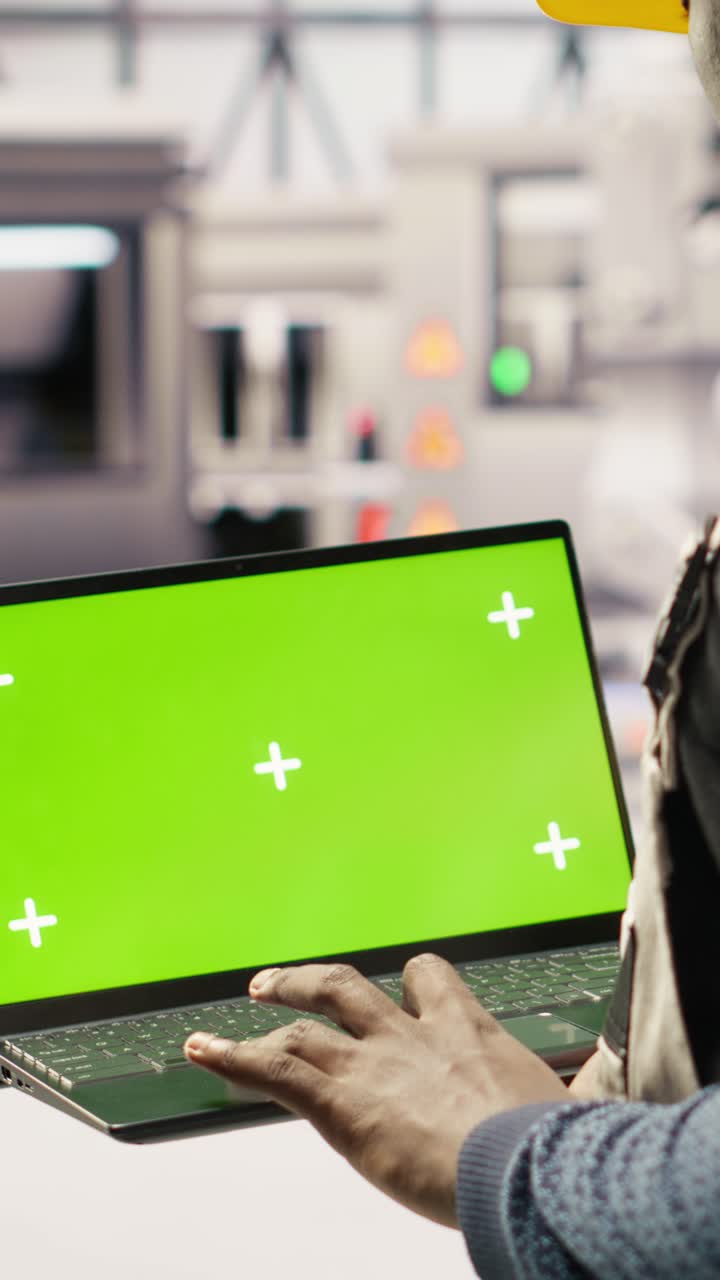 Vertical video Solar panels factory engineer analyzes performance data with green screen laptop
