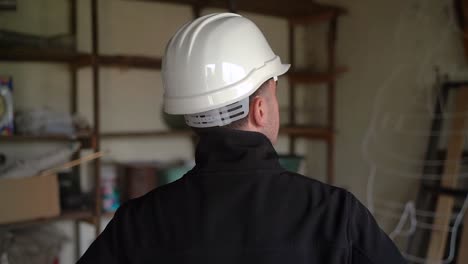 male architect in white hard hat checking out residential space for renovation