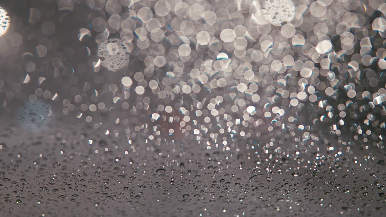 밤에는 도시 조명과 함께 흐릿한 도시 풍경, 흐릿한 배경, 도로에서 기계를 타고, 도시에서 눈이 내리고, 차 앞 유리 기기는 창문에서 눈을 청소합니다.