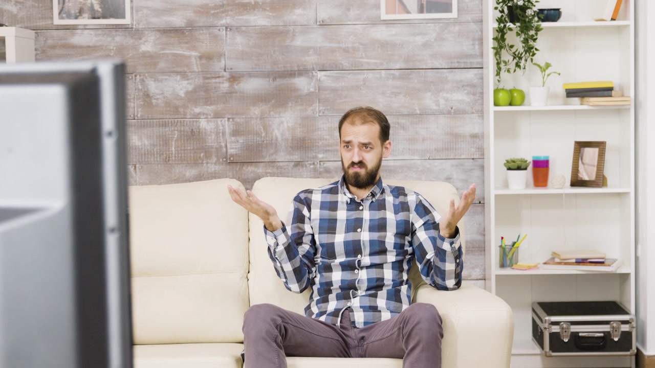 Frustrated Man Watching Television on Sofa at Home