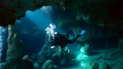 scuba diver exploring a sunlit underwater cave