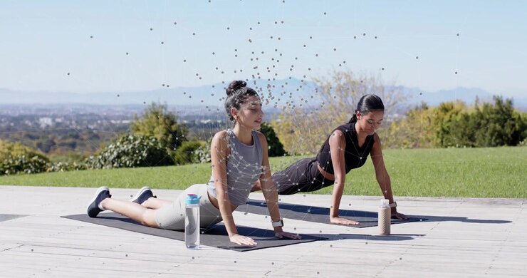 Fitness partners initiating flow through cobra and upward dog on yoga mats overlooking hills