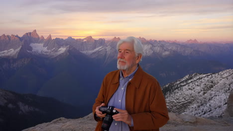 elderly man taking photos of mountain landscape at sunset