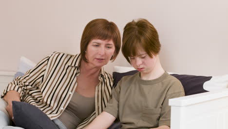 family of two reading book on the sofa