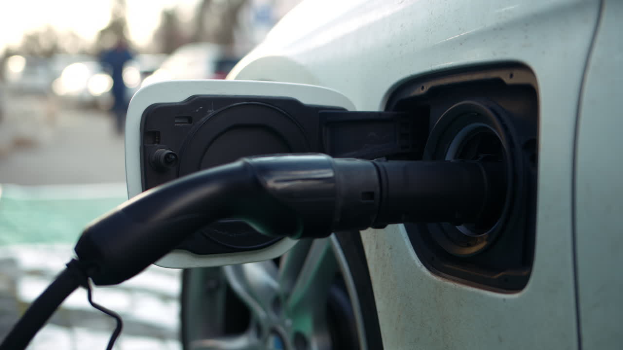 Electric car charger close up, blurred city view with people walking on the background
