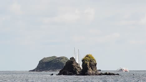 sailboat sailing in between two large rocky cliff islands near manuel antonio national park in costa rica