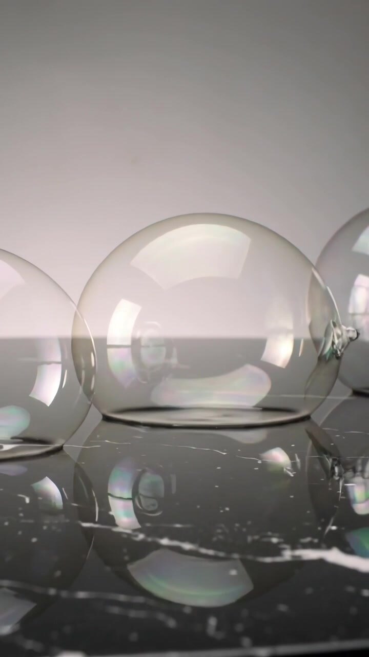 Vertical video: Shifting camera, single soap bubble drifting on marble in studio, showing film neck
