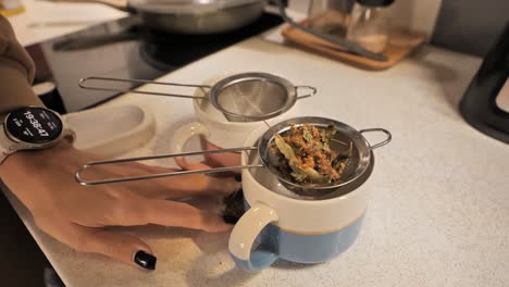 herbal tea blend being added to strainers in cups for brewing - 4k.