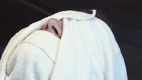 young man was wrapped up in a towel prepared to decorate his beard and mustache in a barber shop close-up