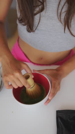 person whisking matcha green tea in a bowl