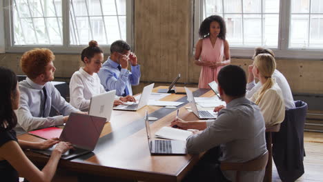 Black-female-boss-stands-talking-at-a-boardroom-meeting