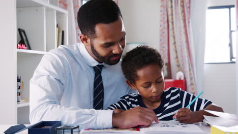 El-Padre-Ayuda-A-Su-Hijo-Con-La-Tarea-En-El-Dormitorio-De-Casa.