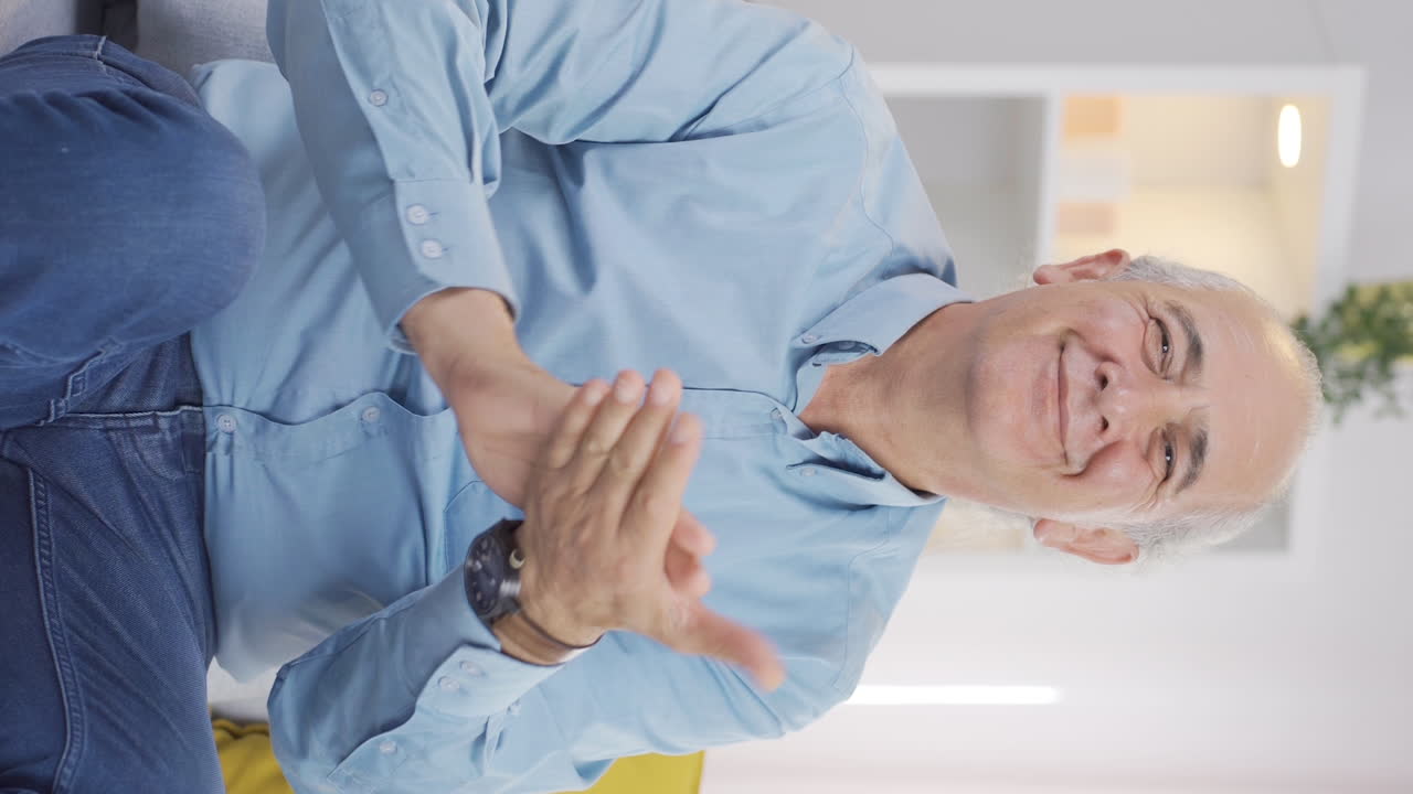 Vertikal video av gammel mann som hilser og klapper til kameraet