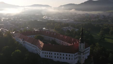 a drone reveals a panoramic view of decin city from above, starting from an old monument at the edge of a forested hill