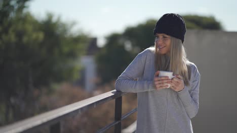 a pretty caucasian woman holding a cup of coffee and enjoying the cold breeze