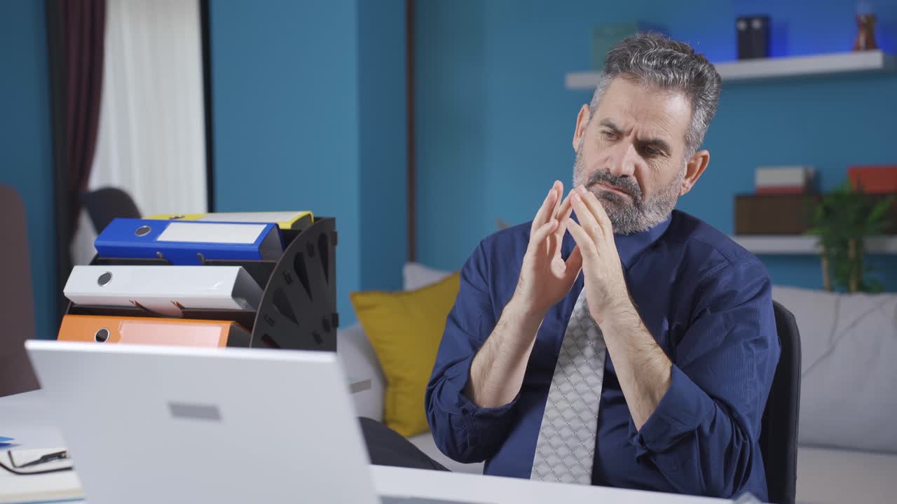hombre de negocios anciano trabajando desde casa en una computadora portátil, esperando pensativo y con calma.