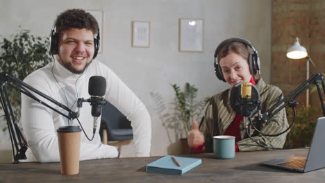 positive male and female vloggers speaking on camera in recording studio