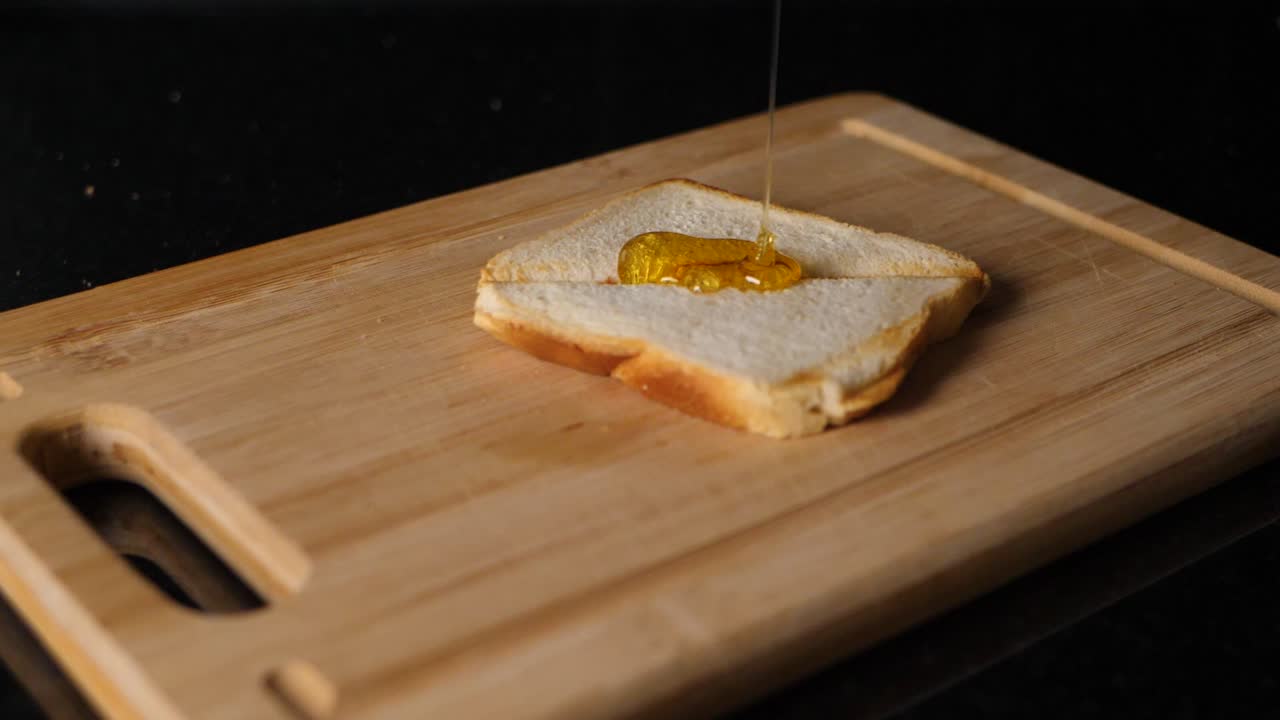 Honey flows down on a toasted bread in slow motion