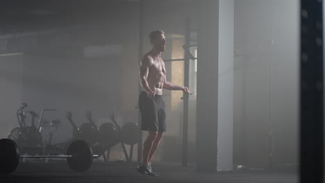 Retrato-De-Un-Joven-Atleta-Saltando-La-Cuerda.-Atleta-Masculino-En-Cámara-Lenta-Haciendo-Ejercicio-Con-Cuerda-Para-Saltar-En-Un-Gimnasio.