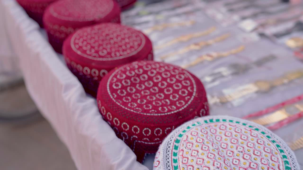 Close-up of colorful embroidered Sindhi topi caps and souvenir items on a street stall in Tharparkar, Sindh, Pakistan, highlighting local culture and crafts