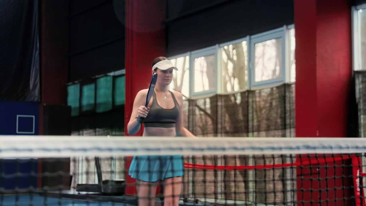 Woman playing pickleball on a blue, inside court