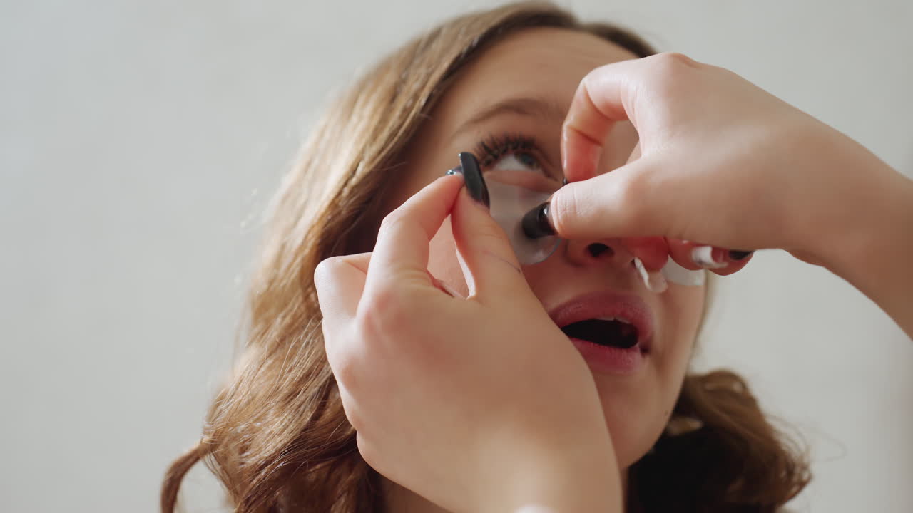Joyful Eyelash Application, Woman With Trusting Expression During Eyelash Extension Session, Serene Woman Shows Subtle Happiness And Confidence As Beauty Technician Works Carefully On Eyelashes