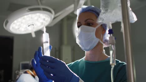 video of caucasian female surgical assistant preparing drip bag in operating theatre