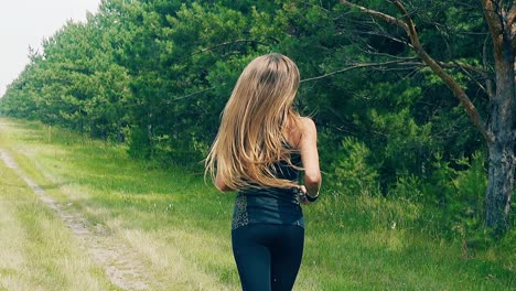 CU-Slow-motion-Back-shot-Young-lady-goes-in-for-sports-in-morning-runs-along-forest