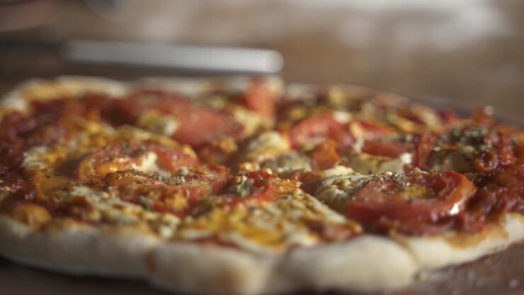 Primo piano di una deliziosa pizza affumicata fatta in casa su un tavolo di legno Slow Motion 60FPS