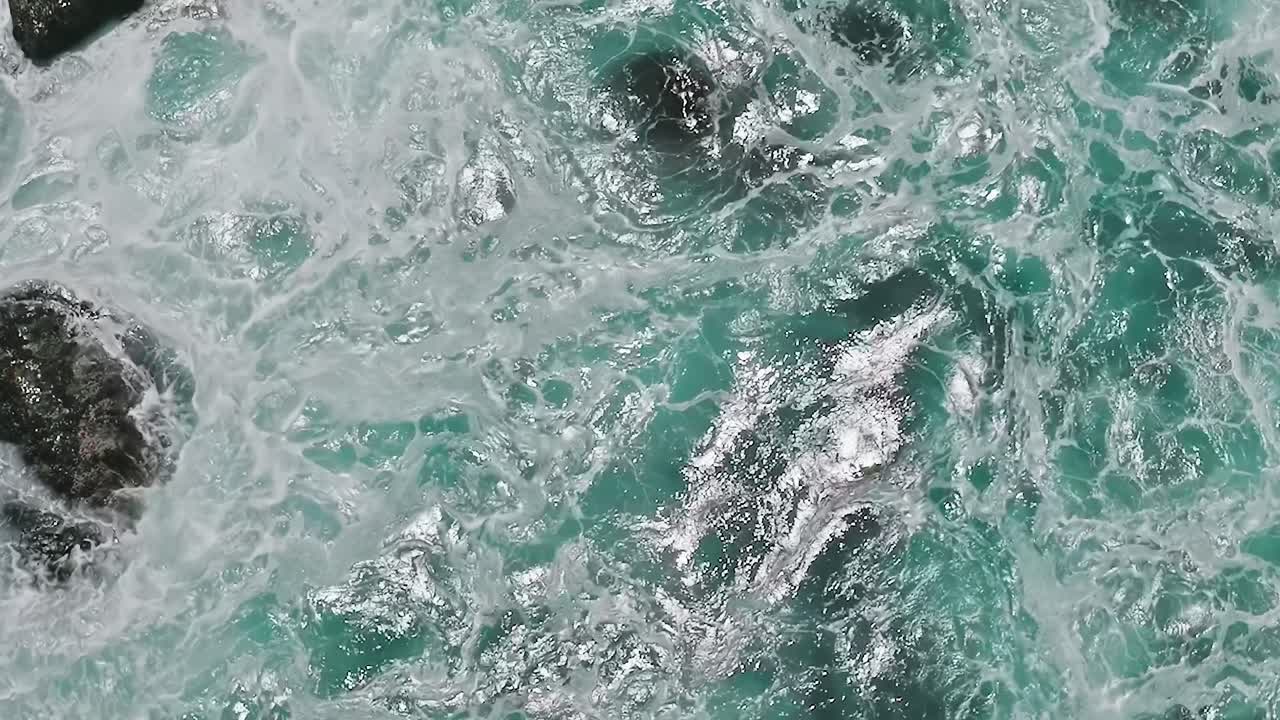 Onde d'acqua si infrangono contro le rocce in California dall'alto