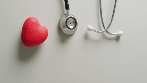 vídeo de un estetoscopio con un corazón rojo sobre fondo gris con espacio para copiar