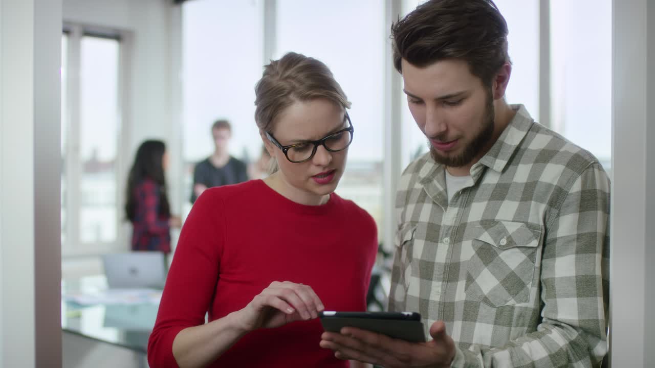 mujer de negocios y joven colega discutiendo algo en una tableta digital
