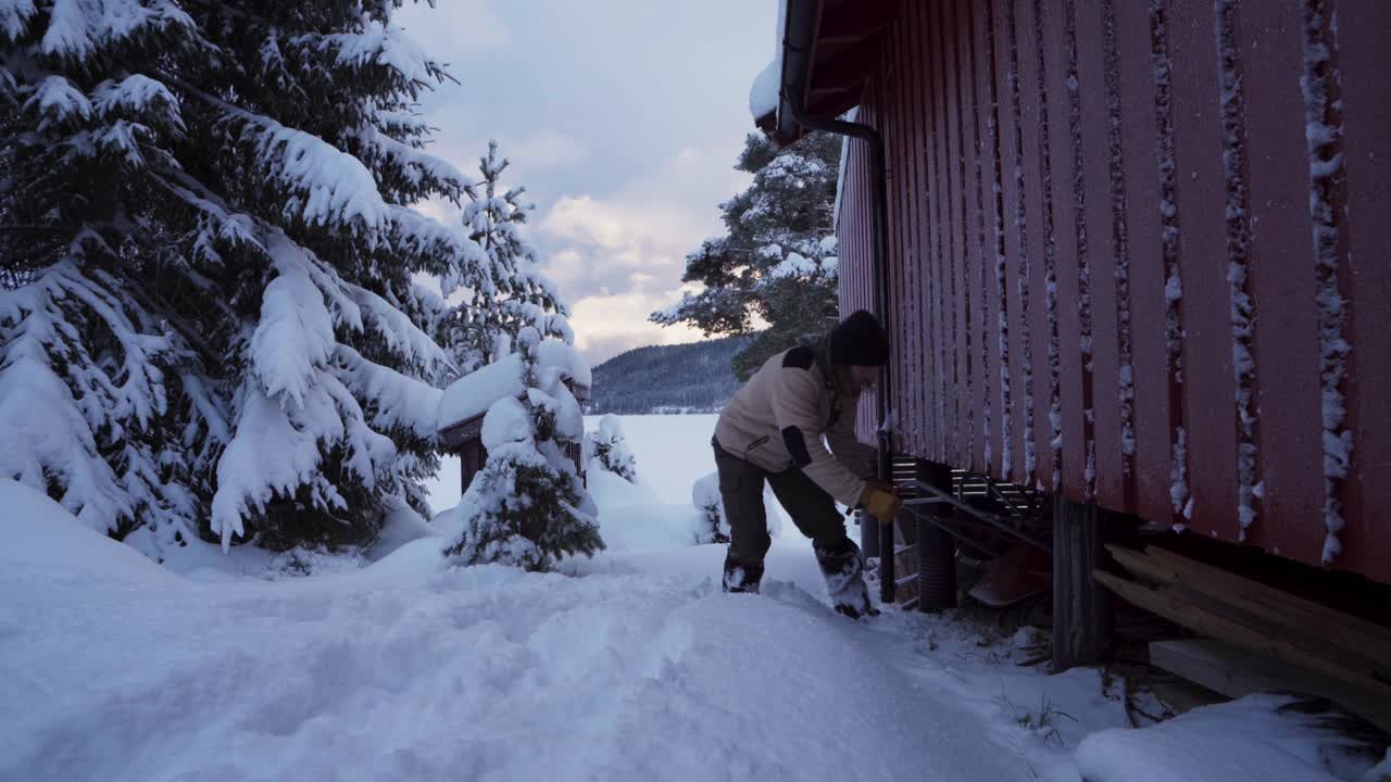남자가 스노우 푸셔를 얻기 위해 오두막 아래를 향해 걷고 있다
